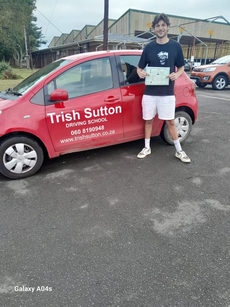 Trish Sutton Driving School learner celebrating a passed test beside the red training car