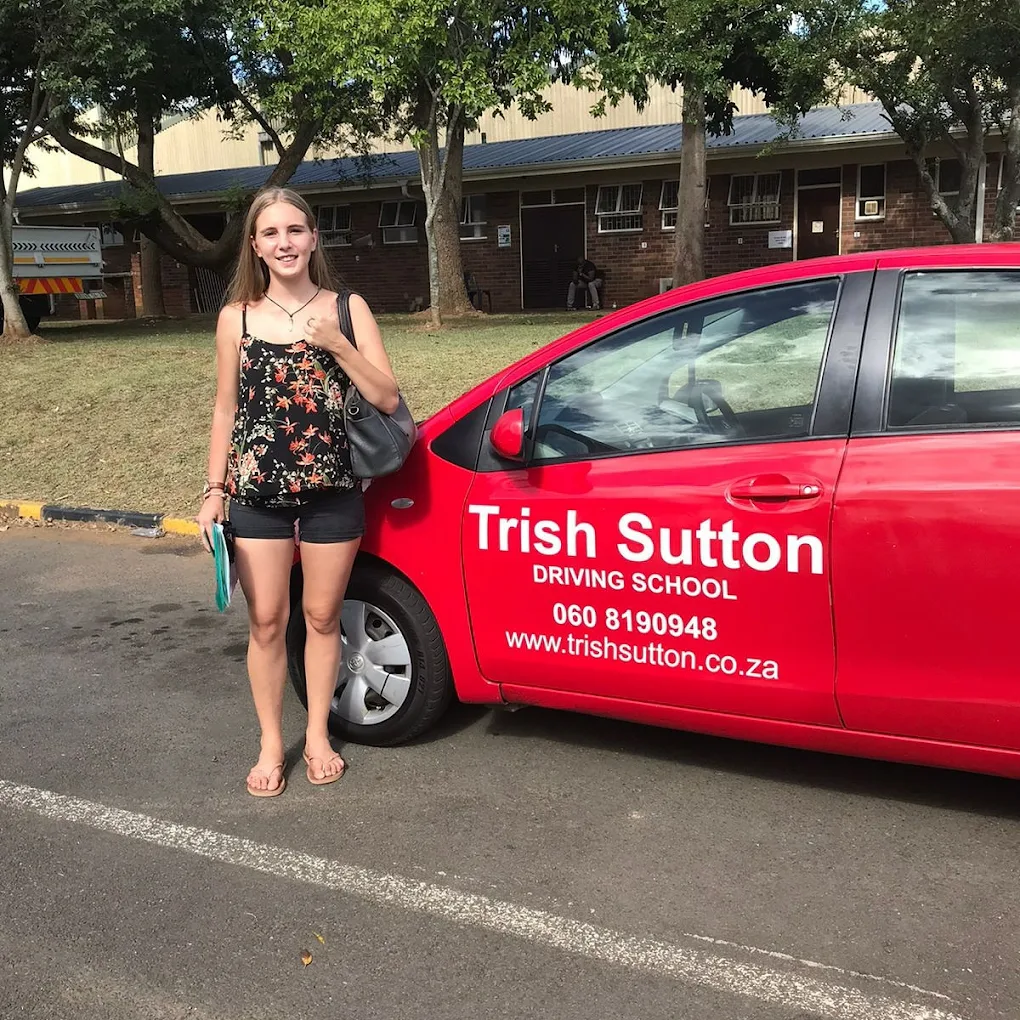 Happy Trish Sutton Driving School student beside the red training car